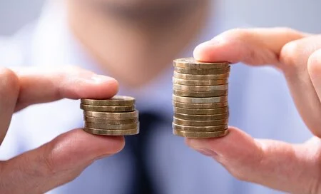 Man Holding Two Coin Stacks To Compare