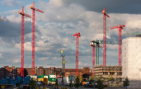 Grossbaustelle mit vielen Kränen vor dramatischem Wolkenhimmel